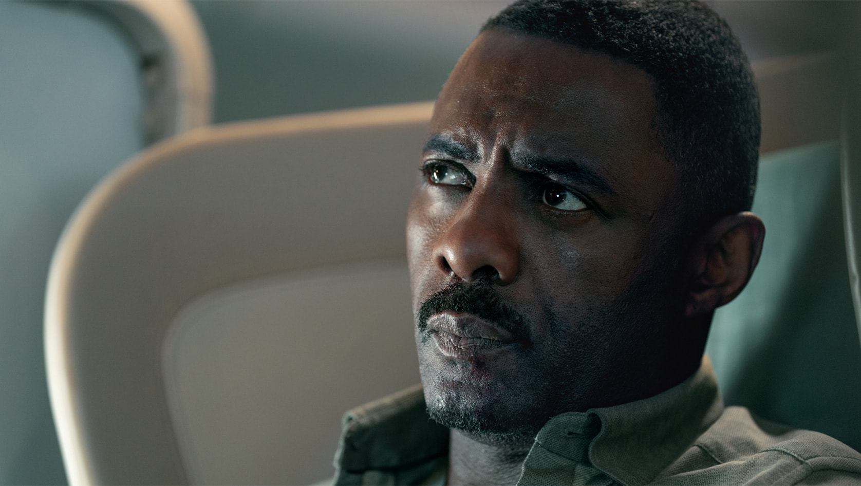 Idris Elba as Sam Nelson sitting on a plane in Apple TV Plus’ Hijack